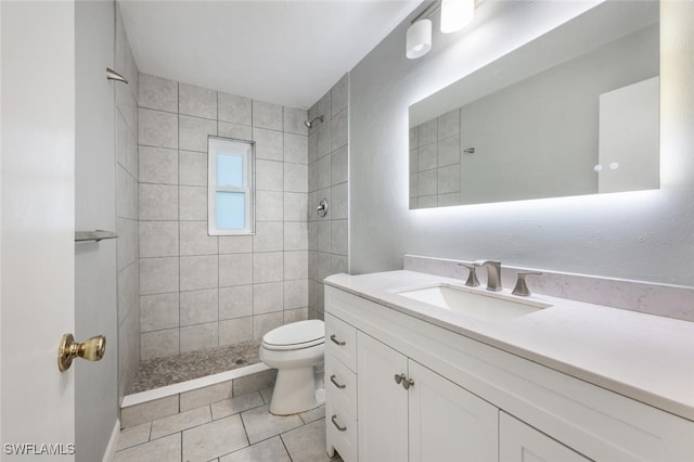 bathroom with vanity, tile patterned floors, toilet, and tiled shower