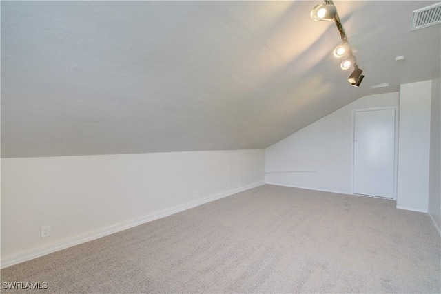 additional living space featuring light colored carpet and vaulted ceiling