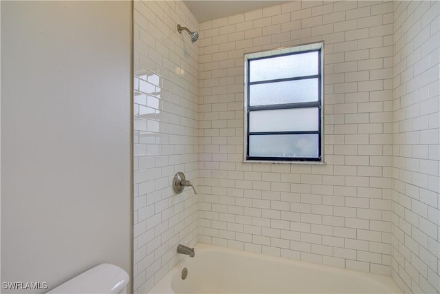 bathroom featuring toilet and tiled shower / bath