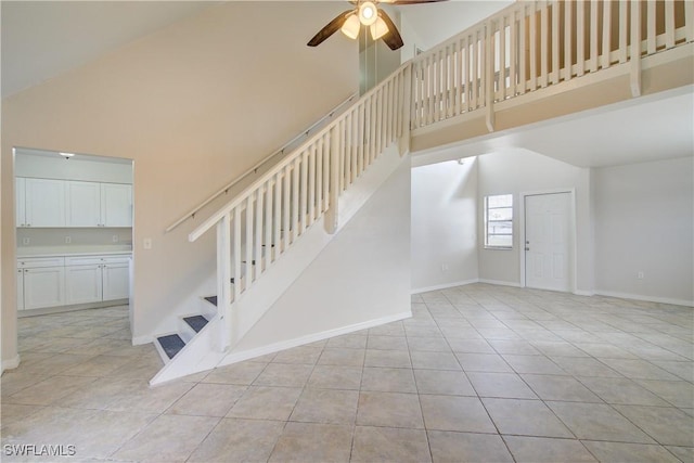 staircase with ceiling fan, high vaulted ceiling, and tile patterned flooring