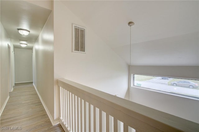 hallway with light wood-type flooring and vaulted ceiling