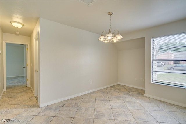 spare room featuring a healthy amount of sunlight, light tile patterned floors, and a notable chandelier