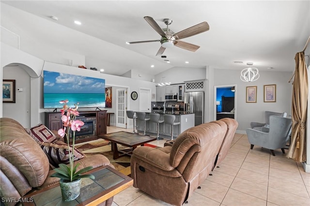 tiled living room with ceiling fan with notable chandelier, lofted ceiling, and a fireplace