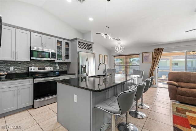 kitchen featuring stainless steel appliances, a kitchen island with sink, sink, decorative light fixtures, and lofted ceiling