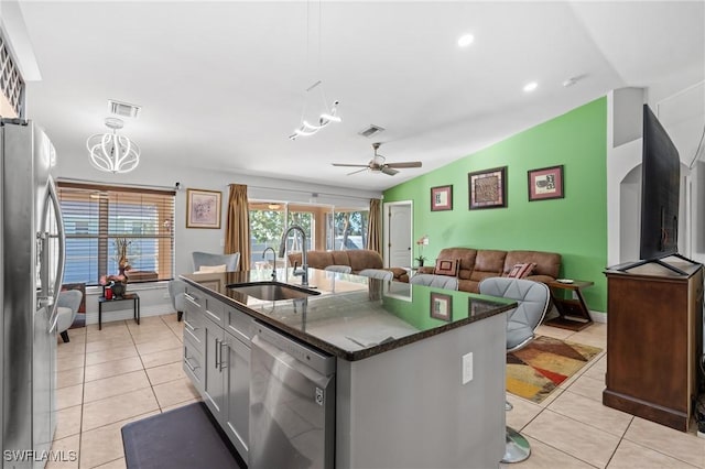 kitchen with ceiling fan, sink, stainless steel appliances, vaulted ceiling, and a center island with sink