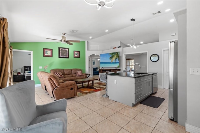 kitchen with ceiling fan, sink, lofted ceiling, gray cabinets, and a center island with sink