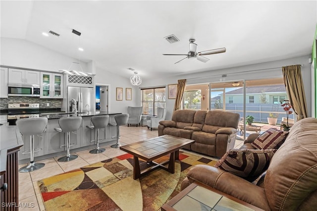 living room with ceiling fan, light tile patterned flooring, sink, and vaulted ceiling