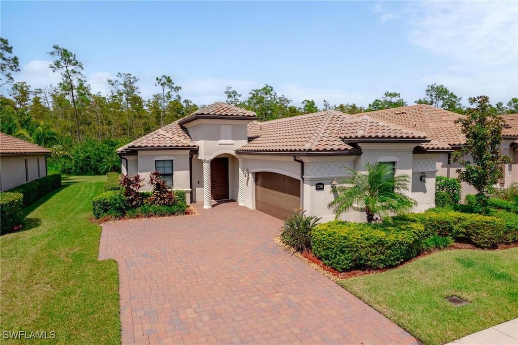 mediterranean / spanish-style house featuring a garage and a front lawn