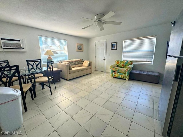 living room featuring ceiling fan, a textured ceiling, and an AC wall unit