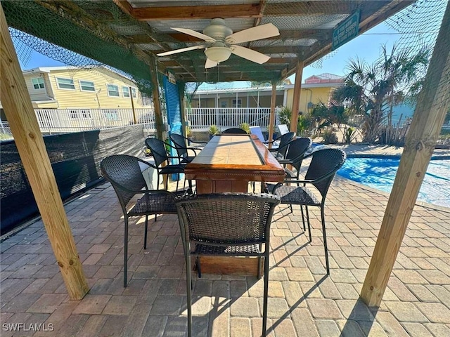 view of patio with a ceiling fan, outdoor dining space, an outdoor pool, and fence