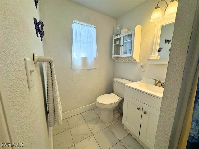 bathroom with marble finish floor, vanity, toilet, and baseboards