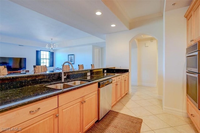 kitchen featuring appliances with stainless steel finishes, light brown cabinetry, sink, dark stone countertops, and light tile patterned floors