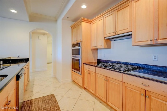 kitchen featuring light tile patterned floors, crown molding, appliances with stainless steel finishes, dark stone countertops, and light brown cabinetry