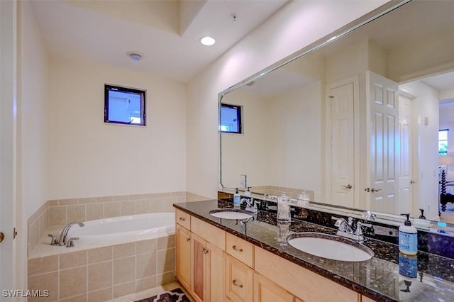 bathroom featuring tiled tub and vanity