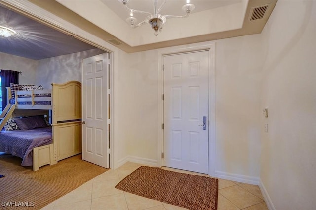 foyer entrance featuring a raised ceiling, a chandelier, and light tile patterned flooring