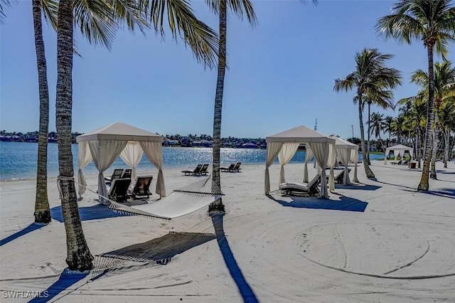 view of dock featuring a view of the beach, a gazebo, and a water view