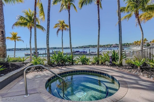 view of swimming pool featuring a hot tub and a water view