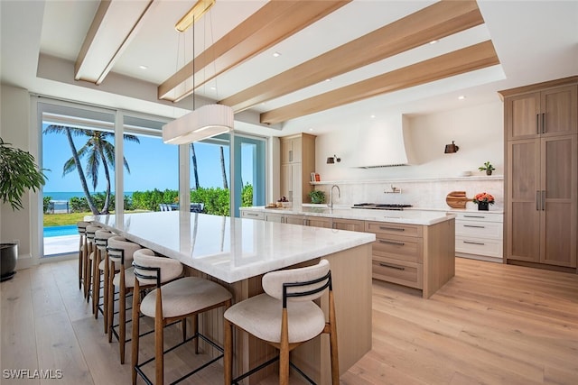 kitchen with backsplash, light wood-type flooring, decorative light fixtures, a kitchen island, and white cabinetry