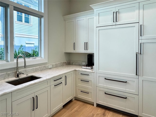 55 13th Ave S, Naples, FL 34102 - kitchen with a sink, white cabinetry, light wood-style flooring, and light stone countertops