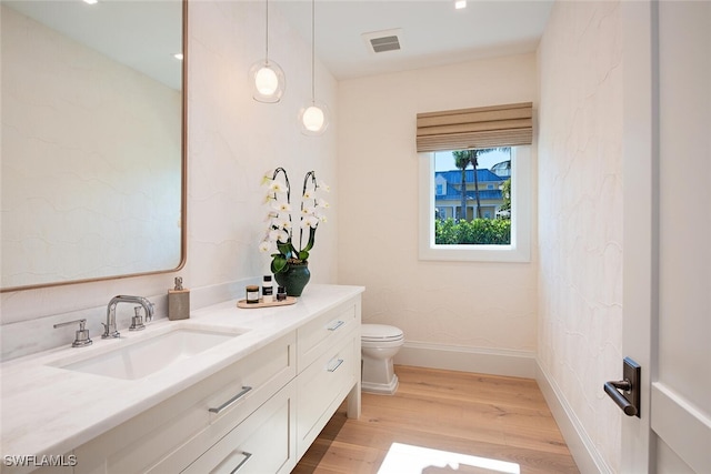 bathroom featuring wood-type flooring, vanity, and toilet