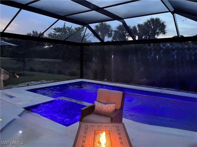 pool at dusk featuring a fire pit, a patio, and glass enclosure