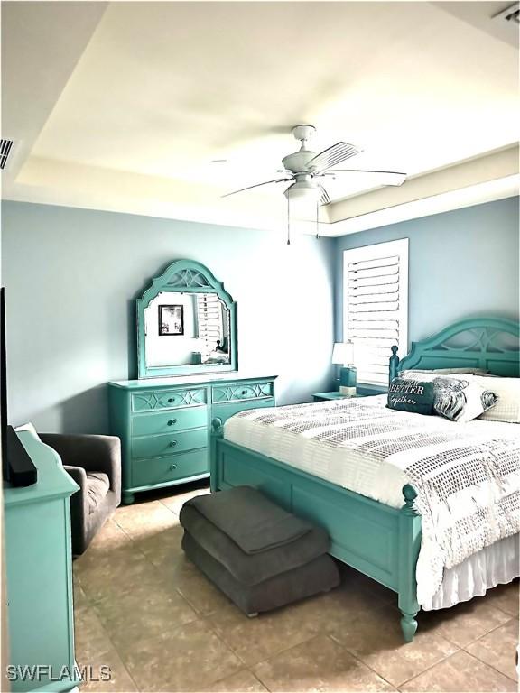 bedroom featuring a raised ceiling and ceiling fan