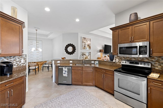 kitchen with appliances with stainless steel finishes, decorative light fixtures, sink, a raised ceiling, and a notable chandelier