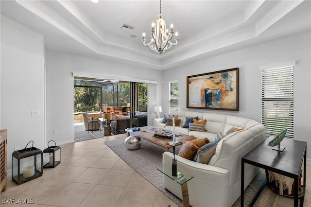 living room featuring a raised ceiling, light tile patterned floors, and a chandelier