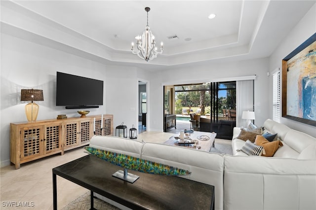 living room featuring light tile patterned floors, a raised ceiling, and an inviting chandelier