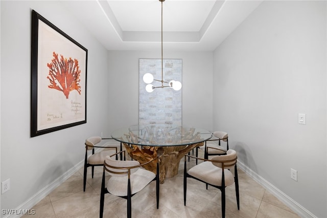 tiled dining space with a tray ceiling and a chandelier