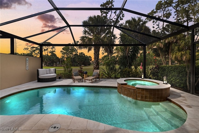 pool at dusk with glass enclosure, an in ground hot tub, and a patio