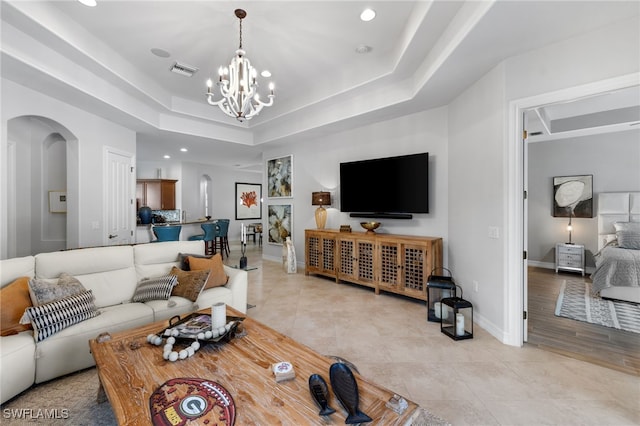 tiled living room with a chandelier and a tray ceiling