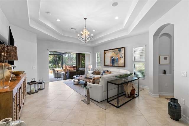 living room with light tile patterned flooring, a tray ceiling, and a chandelier