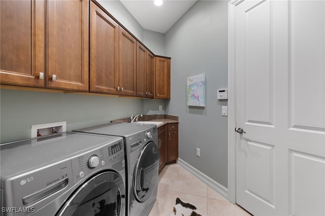 clothes washing area with light tile patterned floors, sink, washer and dryer, and cabinets