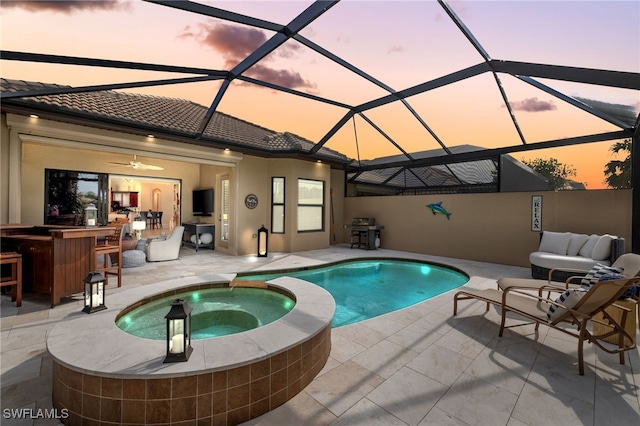 view of pool with an outdoor bar, a patio area, glass enclosure, and an in ground hot tub