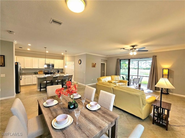 tiled dining space with ceiling fan and ornamental molding