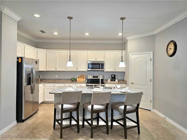 kitchen with white cabinets, stainless steel appliances, hanging light fixtures, and an island with sink