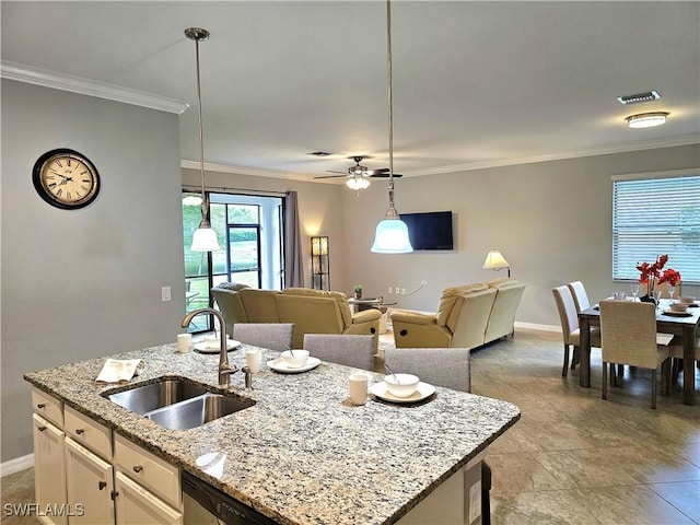 kitchen featuring light stone countertops, sink, an island with sink, pendant lighting, and white cabinets