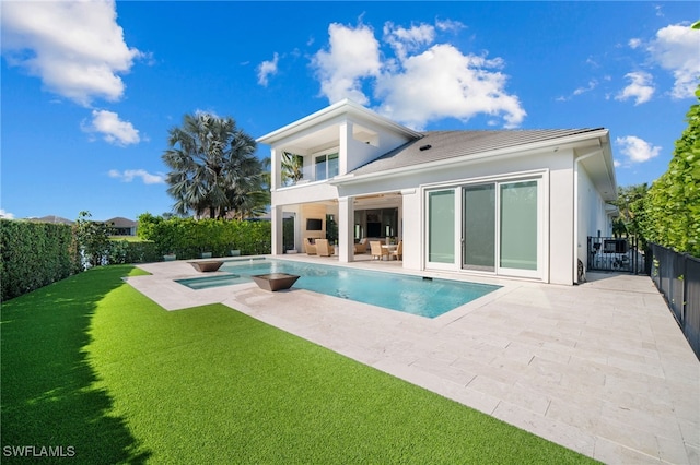 rear view of house featuring a lawn, a patio area, a balcony, an in ground hot tub, and a fenced backyard