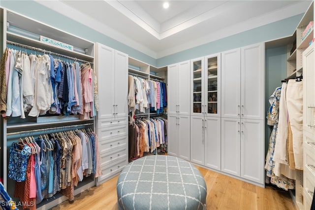 walk in closet with light wood-style flooring and a raised ceiling