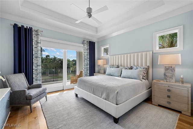 bedroom featuring access to outside, a raised ceiling, ceiling fan, and wood finished floors