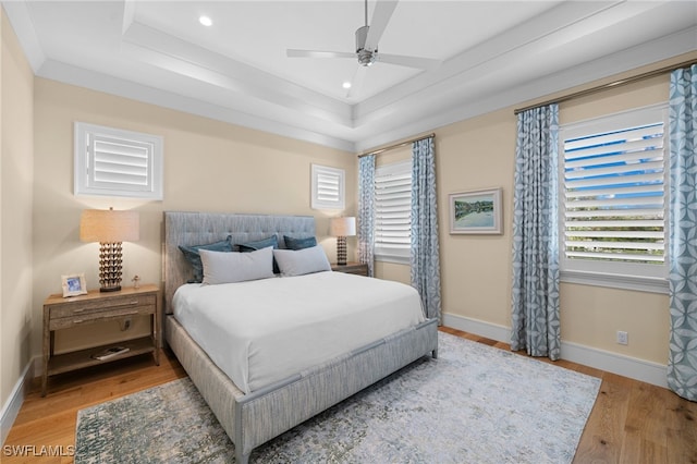 bedroom featuring a tray ceiling, baseboards, light wood finished floors, and recessed lighting