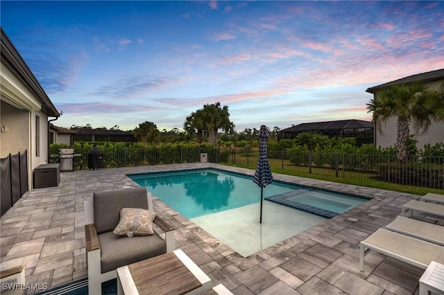 pool at dusk featuring an in ground hot tub, grilling area, and a patio