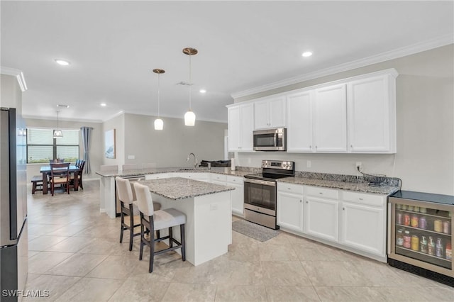 kitchen with white cabinets, appliances with stainless steel finishes, beverage cooler, hanging light fixtures, and kitchen peninsula