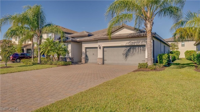 17250 Ashcomb Way, Estero, FL 33928 - view of front of property featuring decorative driveway, stucco siding, an attached garage, a front yard, and stone siding