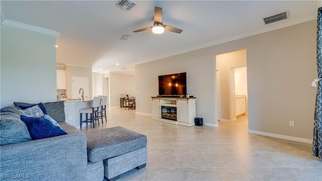 tiled living room with ceiling fan, sink, and ornamental molding