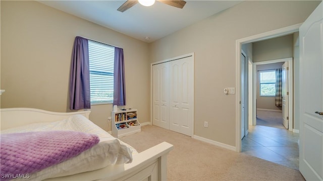 carpeted bedroom with ceiling fan, a closet, and multiple windows