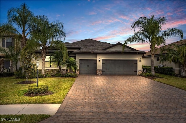 17250 Ashcomb Way, Estero, FL 33928 - ranch-style home featuring stucco siding, an attached garage, decorative driveway, stone siding, and a lawn