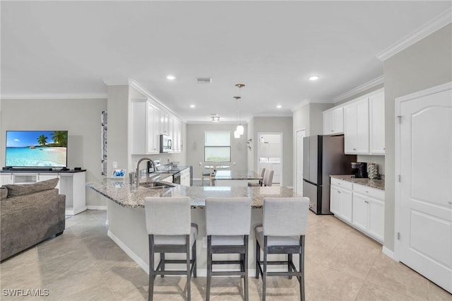 17250 Ashcomb Way, Estero, FL 33928 - kitchen featuring a sink, freestanding refrigerator, white cabinetry, ornamental molding, and light stone countertops