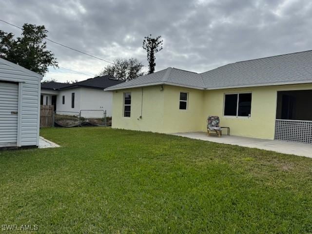 rear view of property with a yard, a patio area, fence, and stucco siding